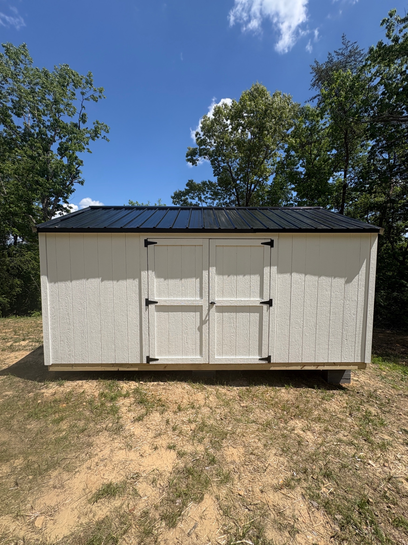 Tan shed with a black Express-Rib metal roof and centered double doors