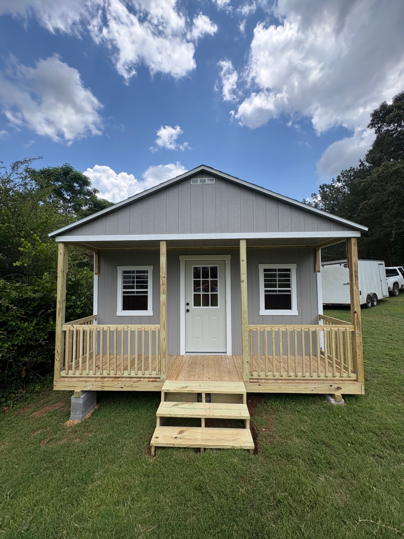 Gray Southern Shed Co. shed with a covered gable porch, railing and steps