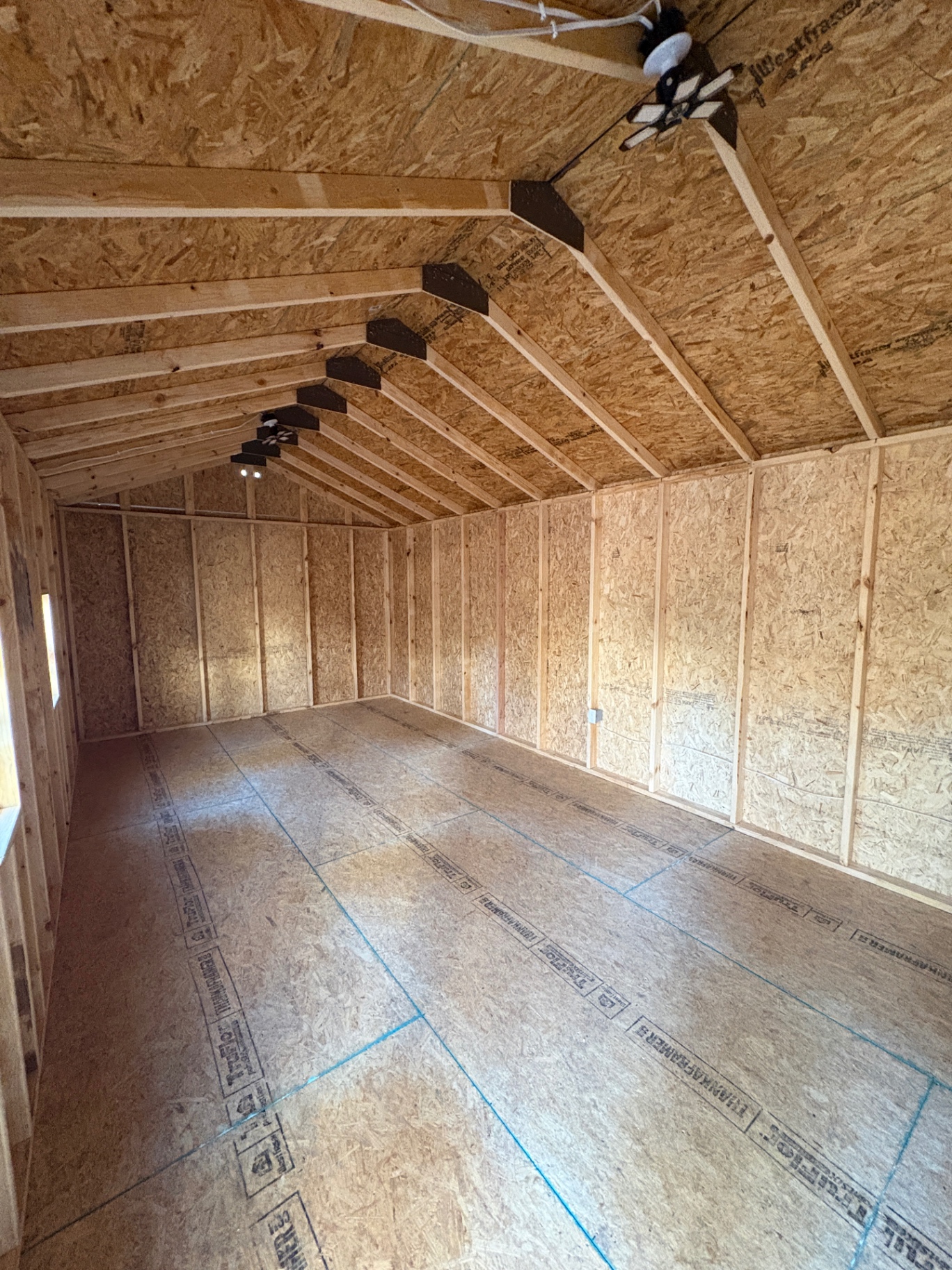 Inside a shed with a ceiling light, wired lighting, framed walls and a TruFloor tongue-and-groove floor