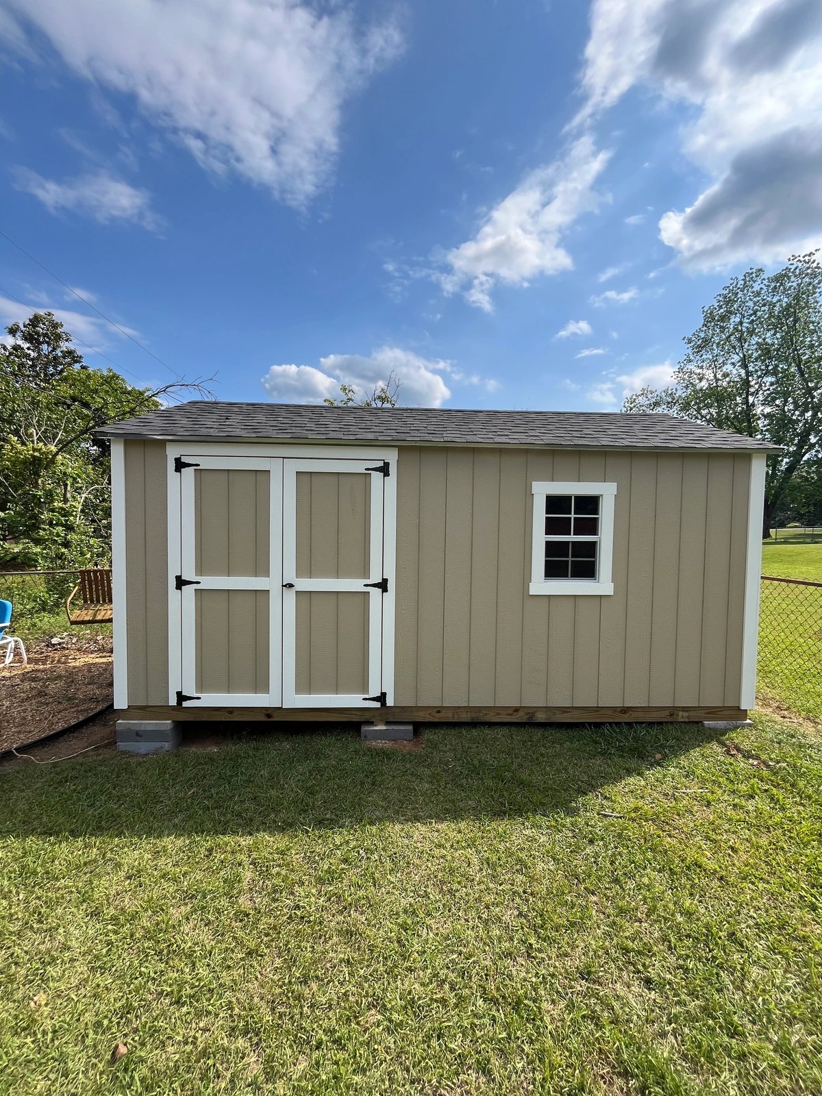 Tan shed with white double doors on the long wall and a single standard window