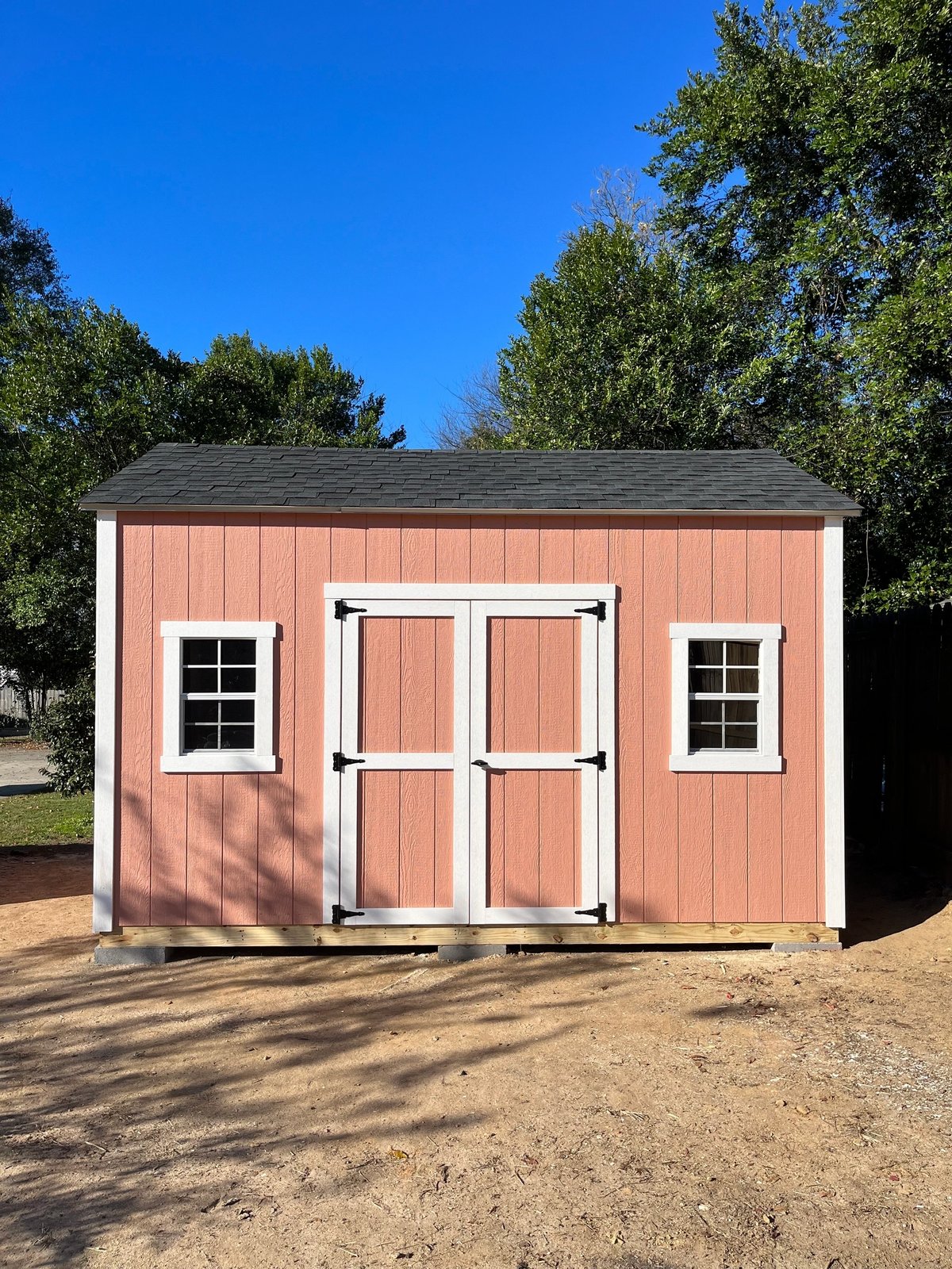 Shed painted a soft coral with white double doors, white trim and a standard window on each side