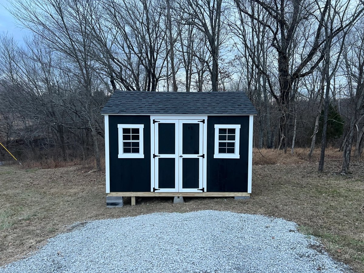 Black gable shed with white trim and standard windows built on a gravel pad